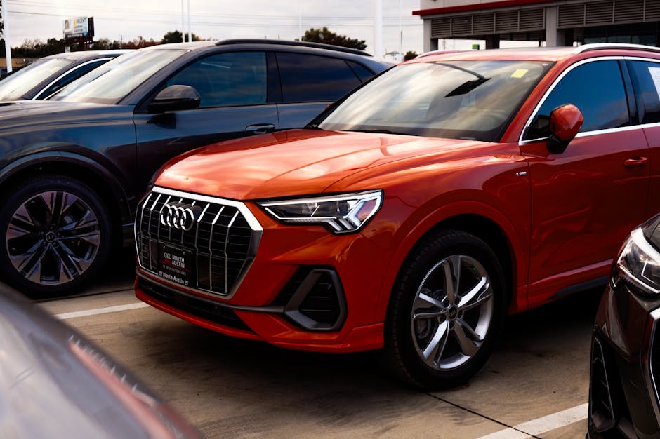 A vibrant orange SUV parked among other vehicles at a car dealership, showcasing modern car design.