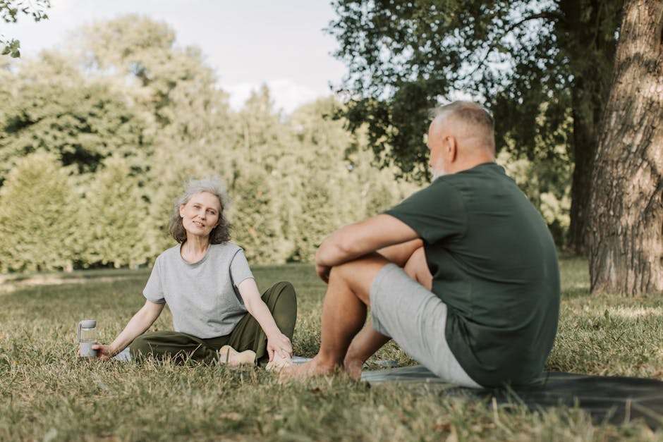 Senior couple practicing yoga and enjoying nature in a sunny park.